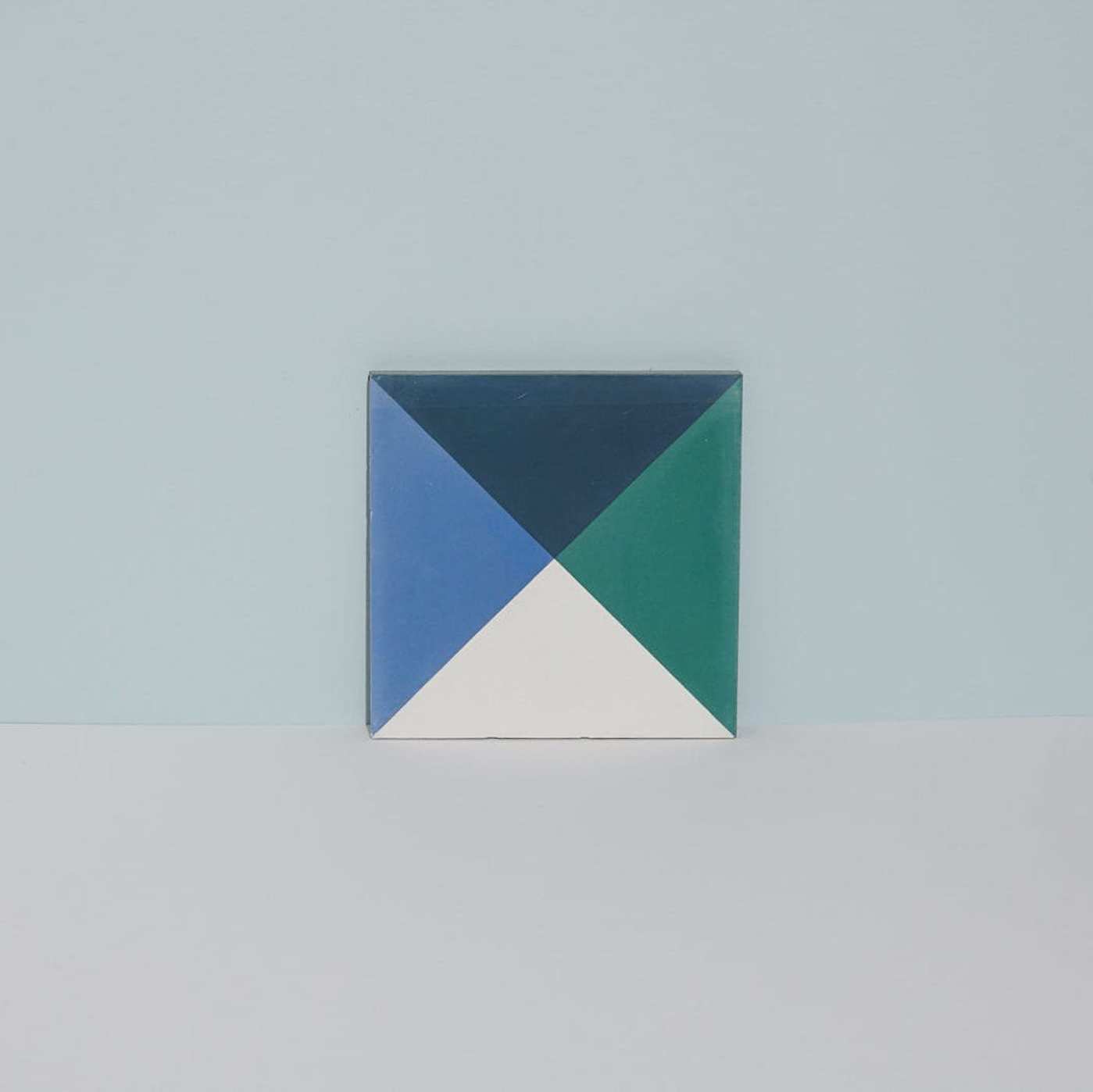 a blue, green, and white tile on a grey surface.