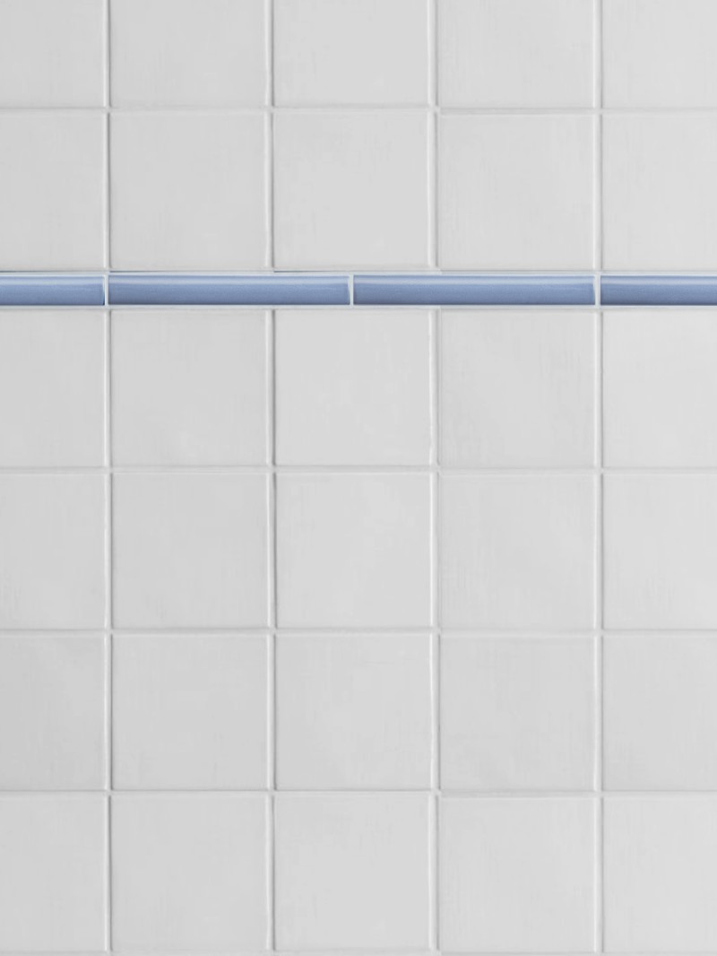 a close up of a white tiled wall with a blue stripe.