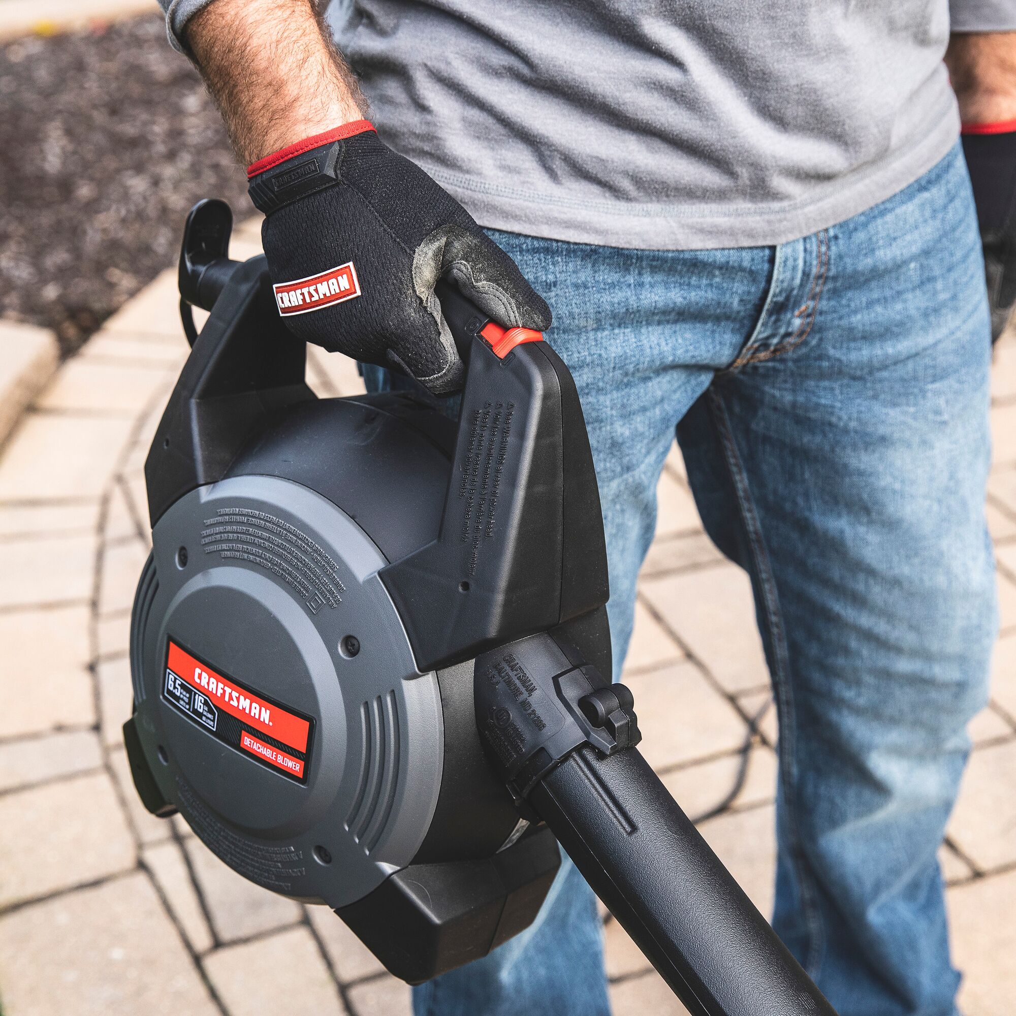 Man holding the removable powerhead from a CRAFTSMAN Wet/Dry Vac on outdoor patio as a leaf blower