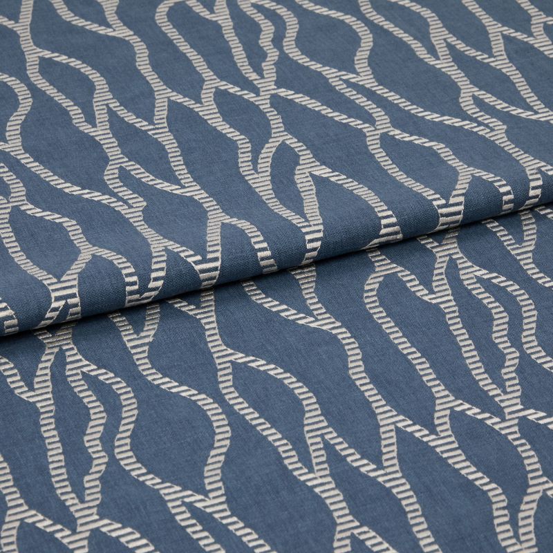 Blue woven fabric with cream embroidered wavy rope pattern, folded over itself, shown in a close-up studio view with soft, even lighting.
