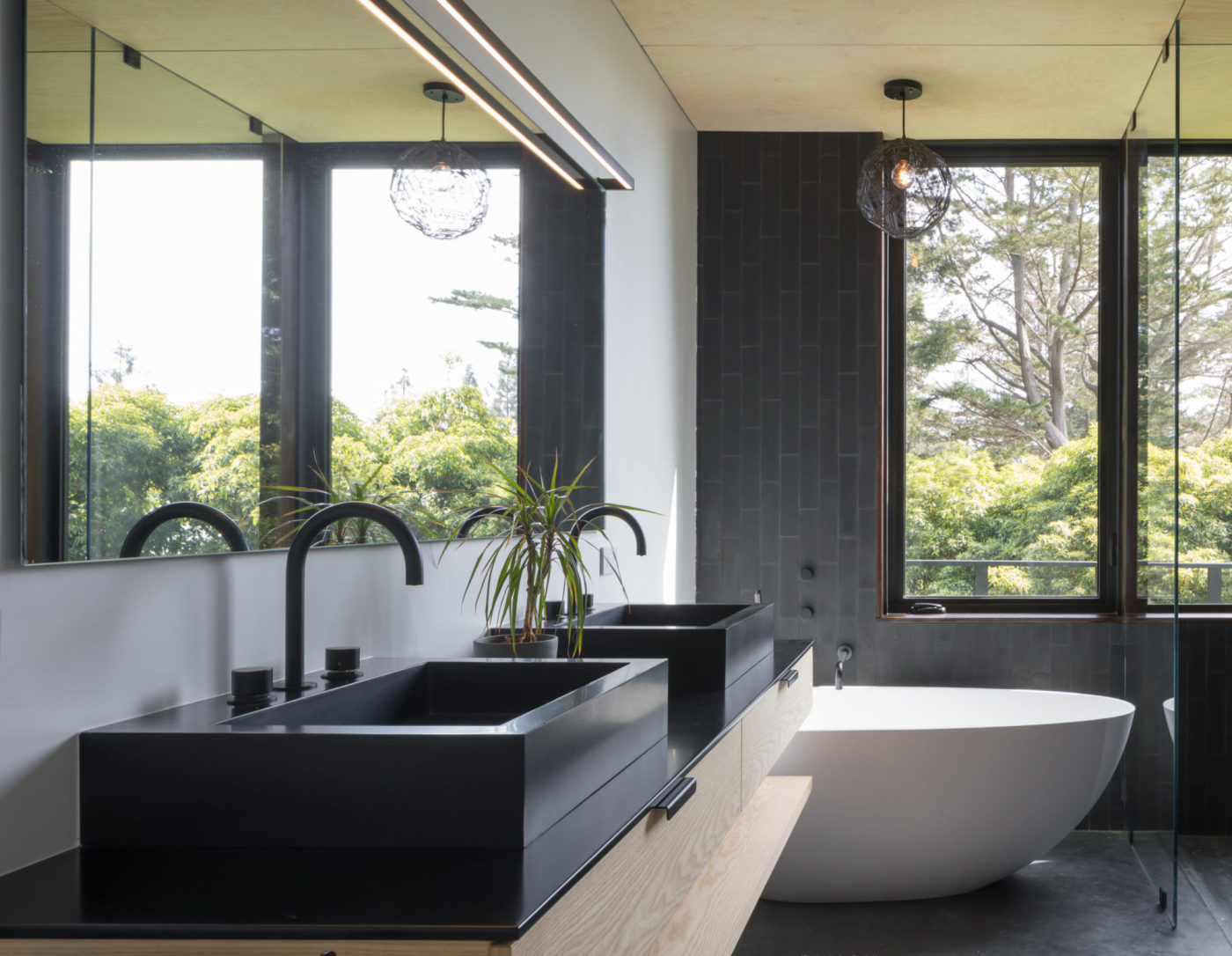 a modern bathroom with two black sinks, a white tub, and large windows.