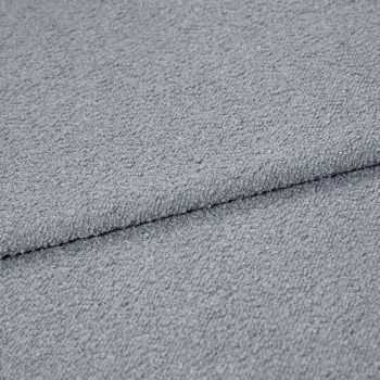 Light-gray bouclÃ© fabric folded once, showing pebbled loop texture; close-up macro view under soft, even lighting on a neutral surface, emphasizing tactile, cozy upholstery material.