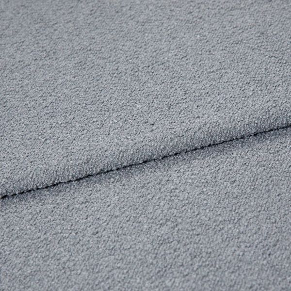 Light-gray bouclÃ© fabric folded once, showing pebbled loop texture; close-up macro view under soft, even lighting on a neutral surface, emphasizing tactile, cozy upholstery material.