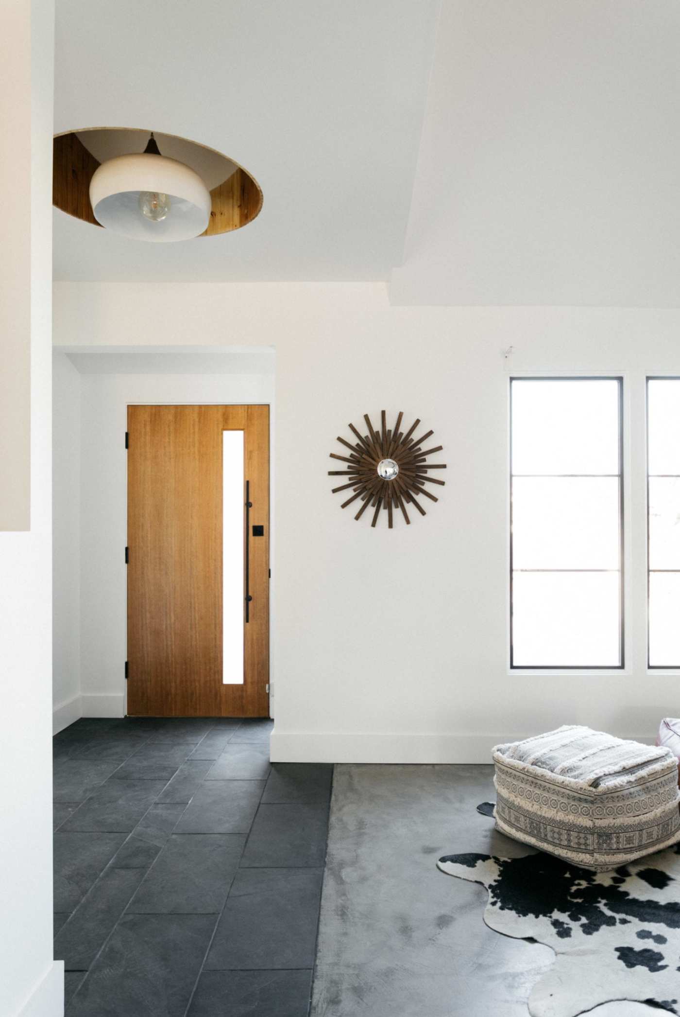 a living room with white walls, a black tile floor and a cowhide rug.