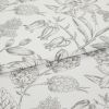White cotton fabric with fine gray botanical sketch print, folded along the center; close-up tabletop view under soft studio lighting, emphasizing floral linework and texture.
