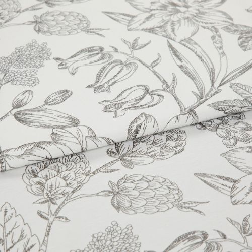 White cotton fabric with fine gray botanical sketch print, folded along the center; close-up tabletop view under soft studio lighting, emphasizing floral linework and texture.
