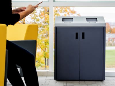 double stream waste and recycling metal powder coated bin with front hinged doors and sloped lid in a university campus