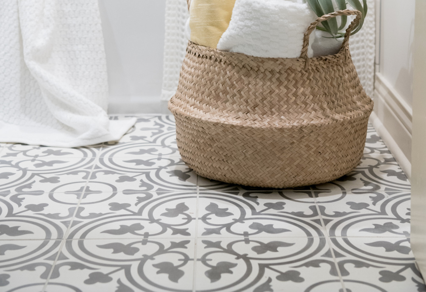 a bathroom with a basket on a grey and white patterned tile floor.