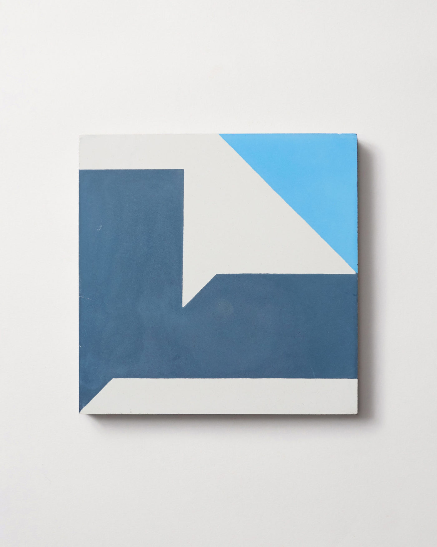 a blue and white tile with an abstract design on a white surface.