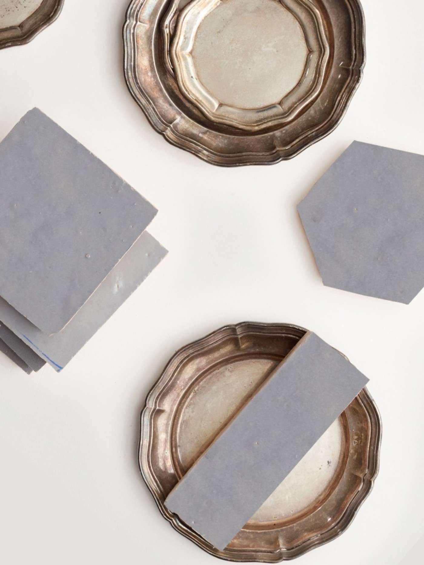 grey tiles and silver plates on a white surface.