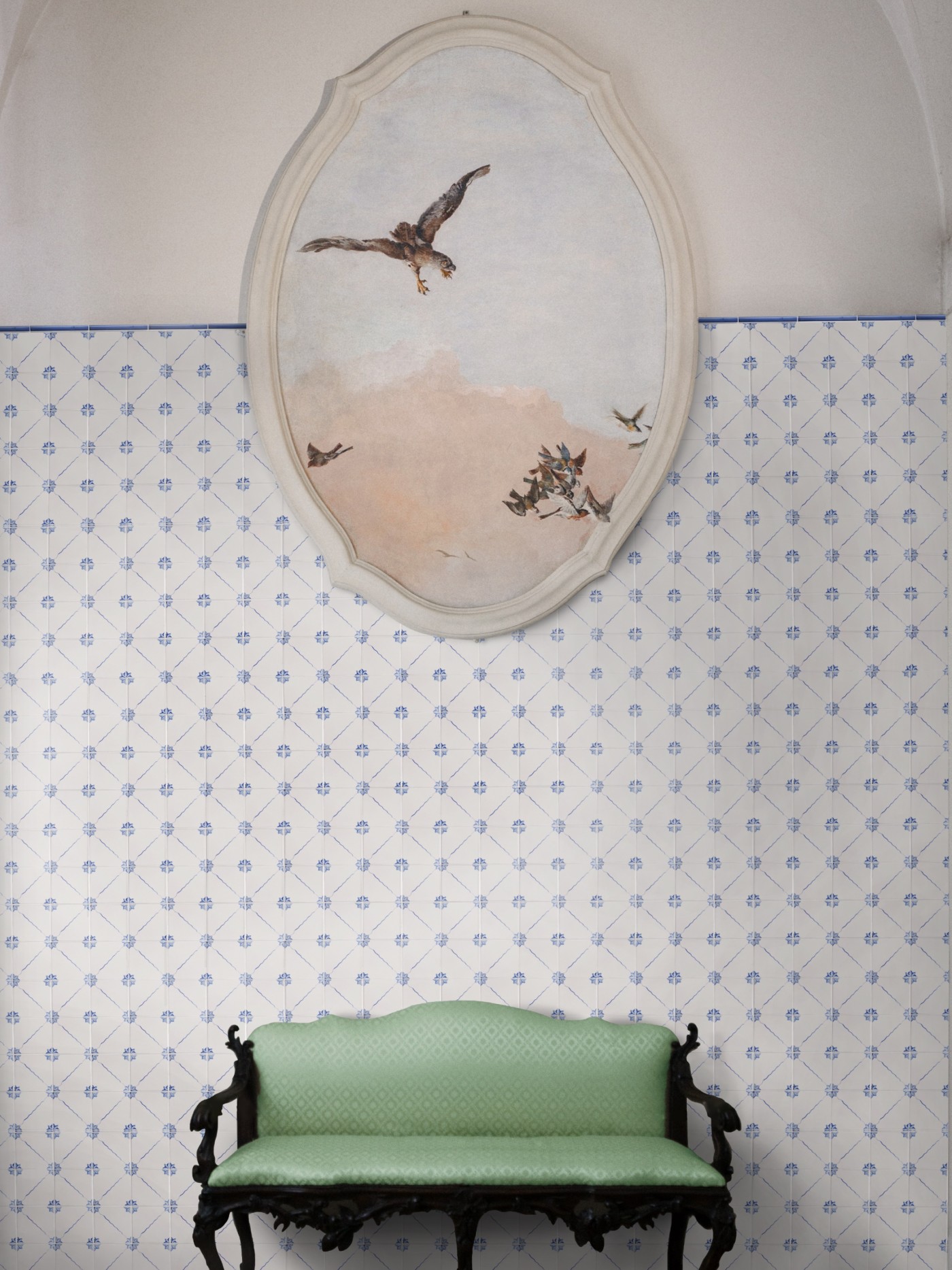 a green bench in front of a blue and white tiled wall with a painting of a bird.