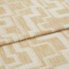 Curtain fabric folded and layered, woven beige cloth with raised cream geometric square/maze pattern; close-up textile shot on flat surface with soft, neutral lighting.