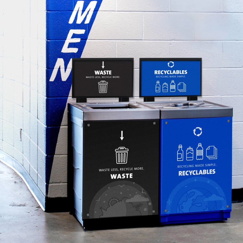 waste and recyclables bins with body signs and sign frames placed beside a washroom in a stadium