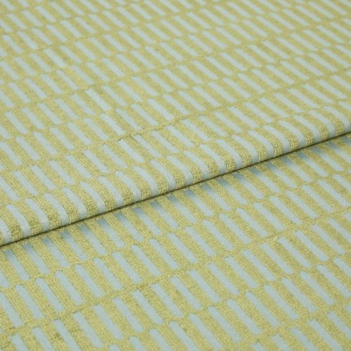 Textile fabric with raised yellow‑green rectangular grid pattern, folded once along a horizontal seam and overlapping, close-up studio-lit sample on a pale blue ground, showing textured weave.
