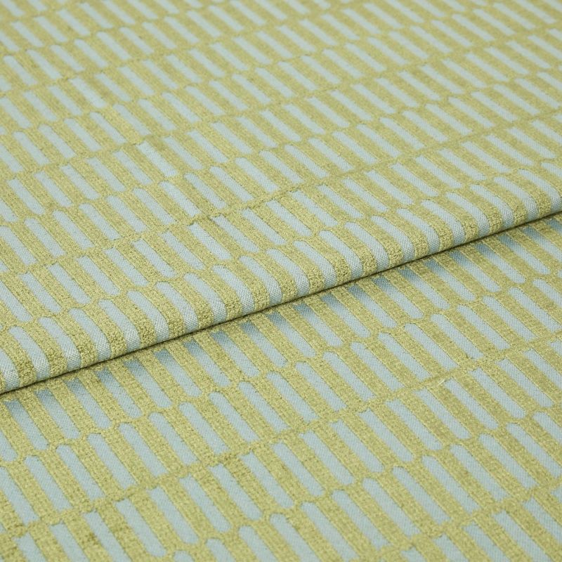 Textile fabric with raised yellowâ€‘green rectangular grid pattern, folded once along a horizontal seam and overlapping, close-up studio-lit sample on a pale blue ground, showing textured weave.