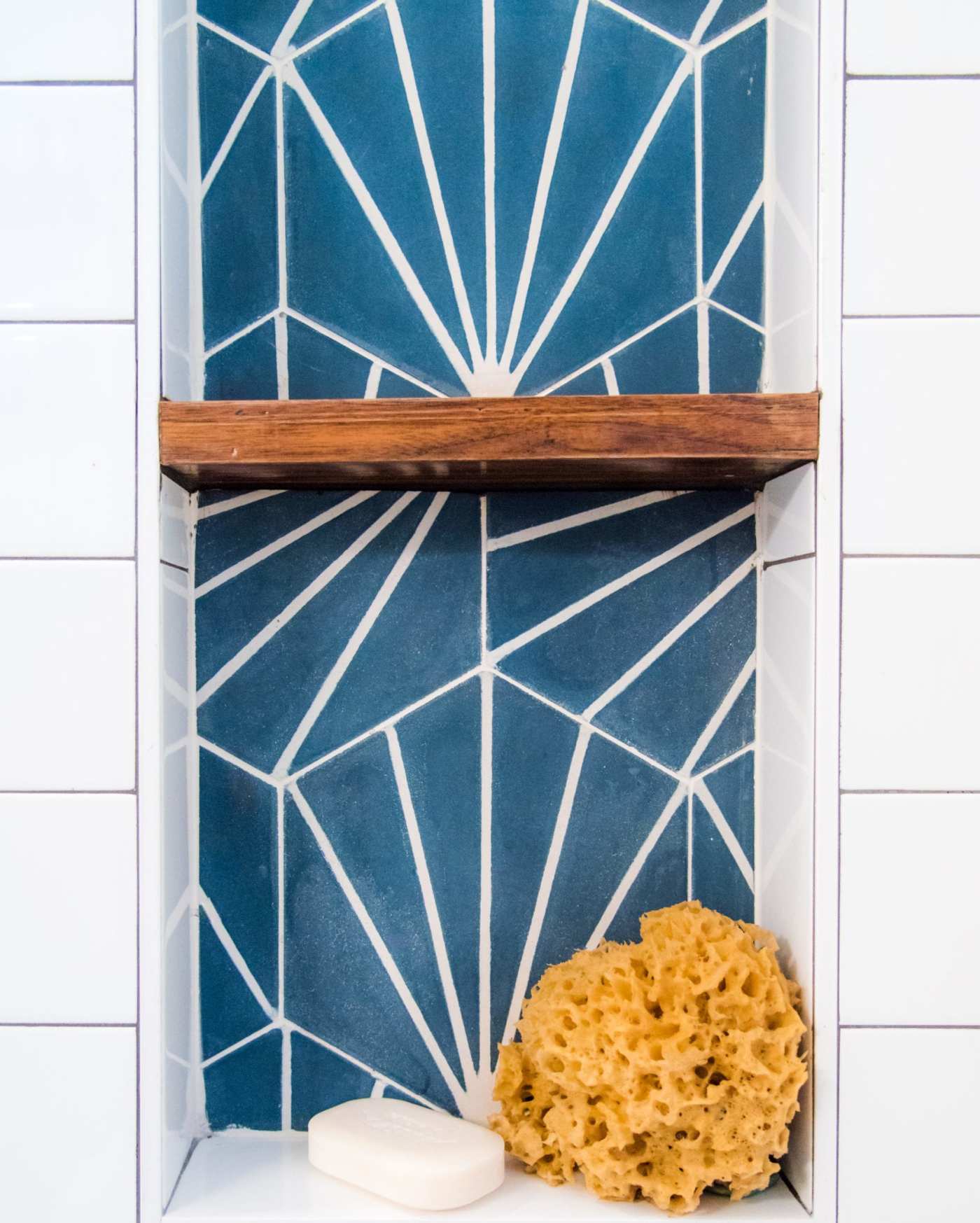 a blue tiled shelf in a bathroom with soap and a sponge.