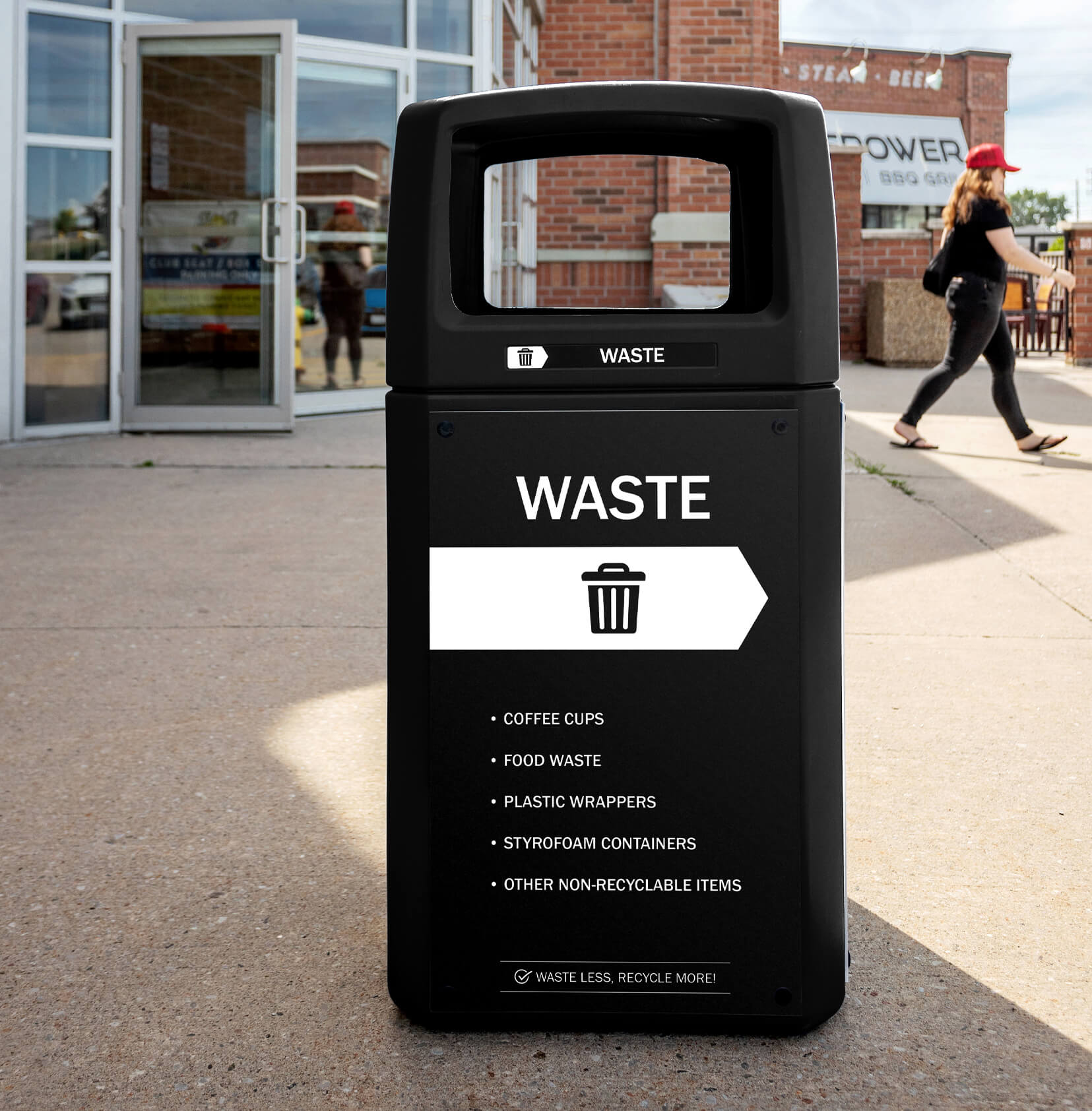 black waste bin made from post-consumer recycled plastic outside of a sports arena with body signs and labels
