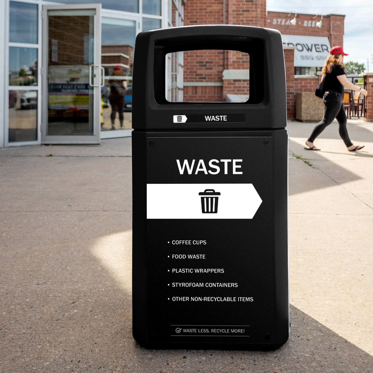 black waste bin made from post-consumer recycled plastic outside of a sports arena with body signs and labels
