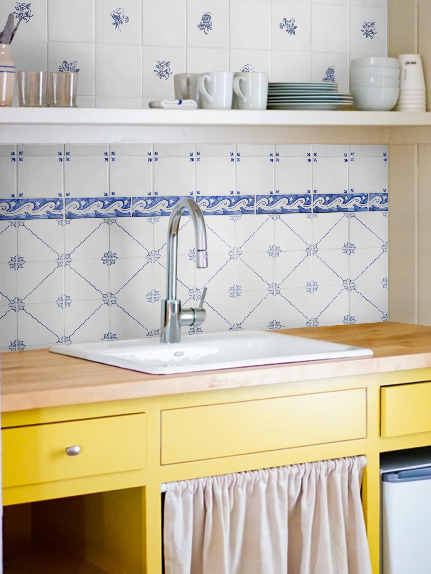 a kitchen with yellow drawers and a blue and white tiled sink backsplash.