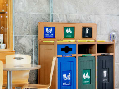 triple stream recycling waste and organics collection container with color-coded doors signs and openings in a hospital cafe