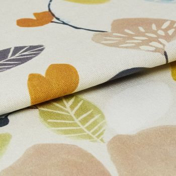 Cream curtain fabric with stylized mustard, olive, beige and purple leaves and flowers, folded and layered to show woven texture, photographed close-up on a flat surface under soft studio lighting.