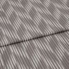 Folded curtain fabric sample with narrow, irregular vertical grey and off-white stripes; folded edge across center, shown close-up on a neutral surface under soft, diffuse lighting.