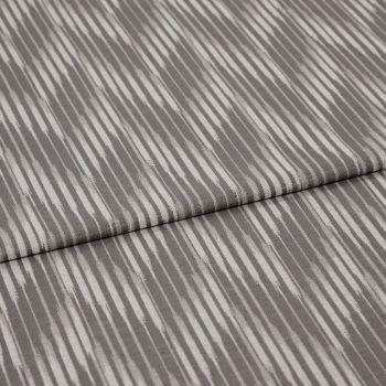 Folded curtain fabric sample with narrow, irregular vertical grey and off-white stripes; folded edge across center, shown close-up on a neutral surface under soft, diffuse lighting.
