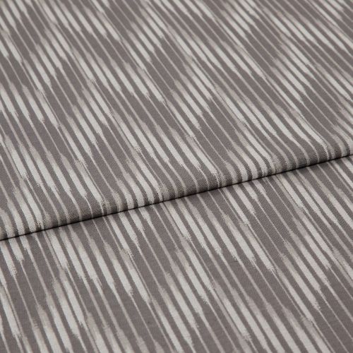 Folded curtain fabric sample with narrow, irregular vertical grey and off-white stripes; folded edge across center, shown close-up on a neutral surface under soft, diffuse lighting.