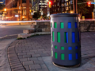grey powder coated steel waste and recycling container with a durable plastic lid at a busy city intersection