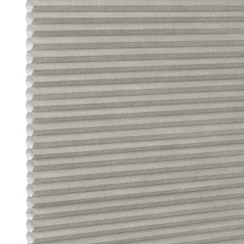 Honeycomb cellular fabric blind with horizontal pleats and textured beige finish, fully lowered and closed, diffusing soft light; set against a neutral, evenly lit wall with narrow white margin left.