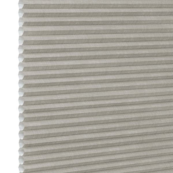 Honeycomb cellular fabric blind with horizontal pleats and textured beige finish, fully lowered and closed, diffusing soft light; set against a neutral, evenly lit wall with narrow white margin left.