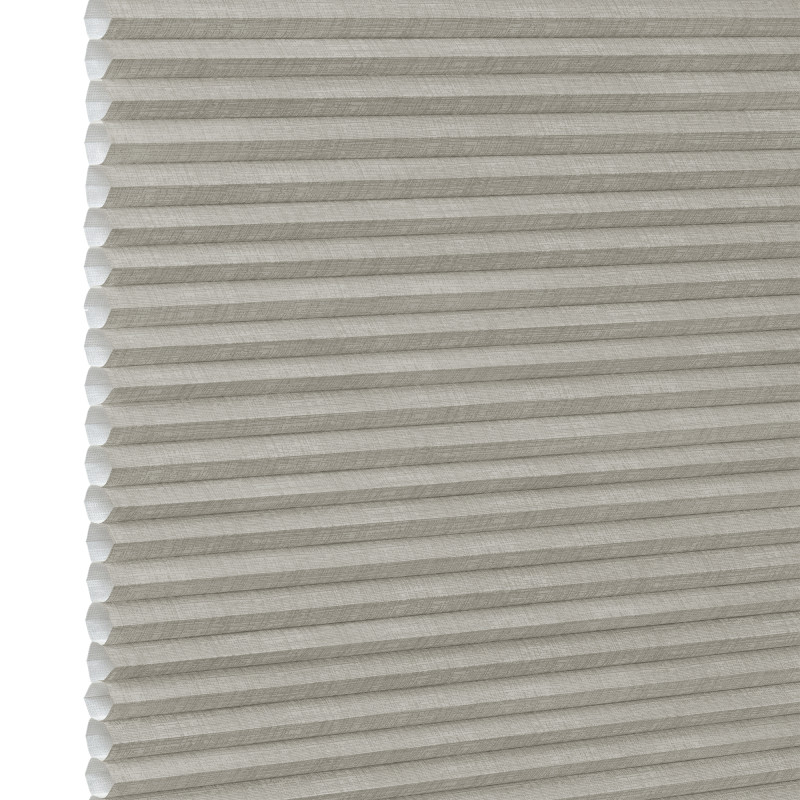 Honeycomb cellular fabric blind with horizontal pleats and textured beige finish, fully lowered and closed, diffusing soft light; set against a neutral, evenly lit wall with narrow white margin left.