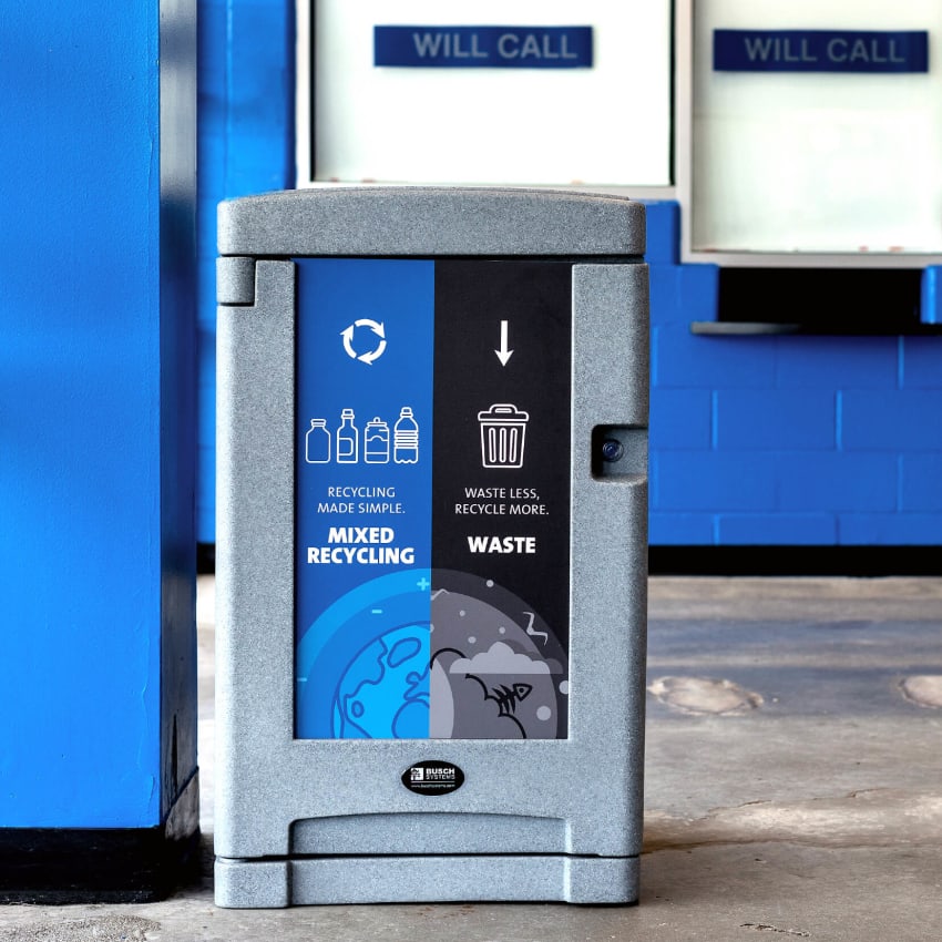 double grey plastic trash and recycling bin with large signs and door lock inside a hockey arena