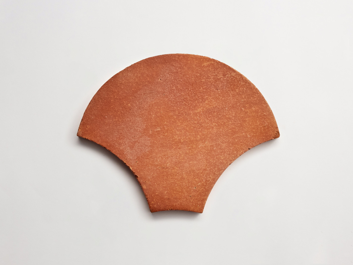 a fan made of red clay on a white surface.