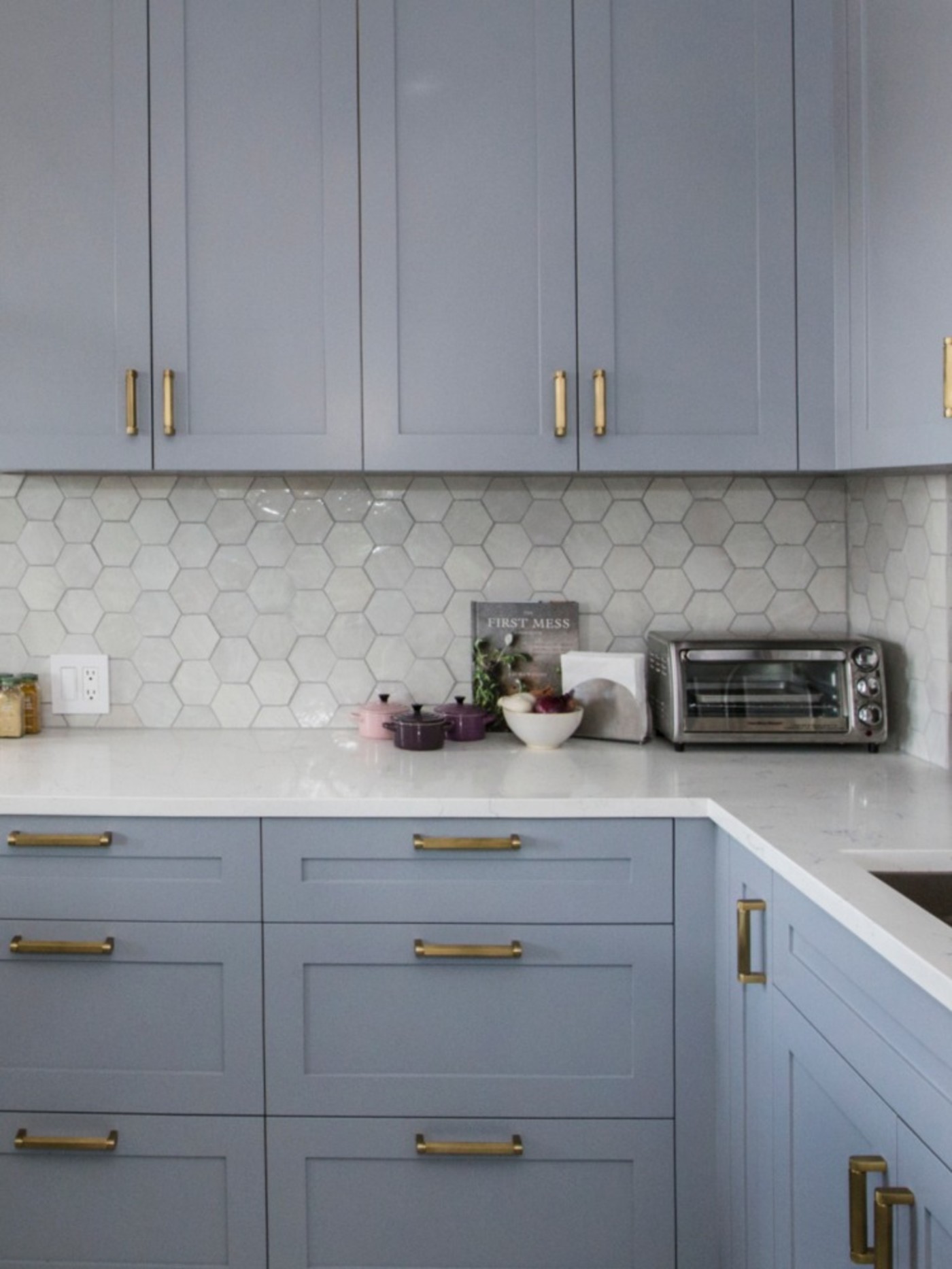 a kitchen with blue cabinets and gold hardware.