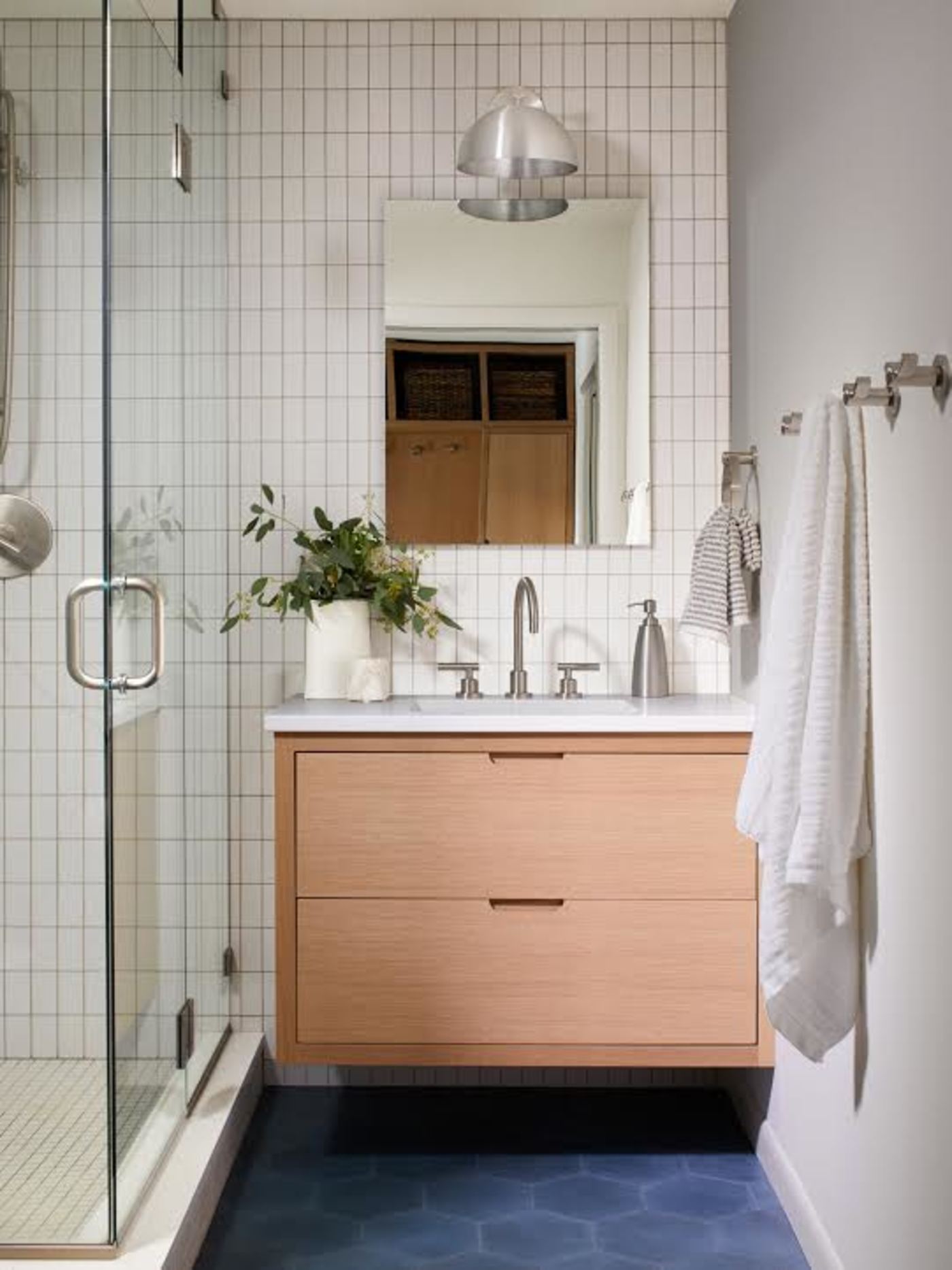 a bathroom with a blue tile floor and a shower stall.