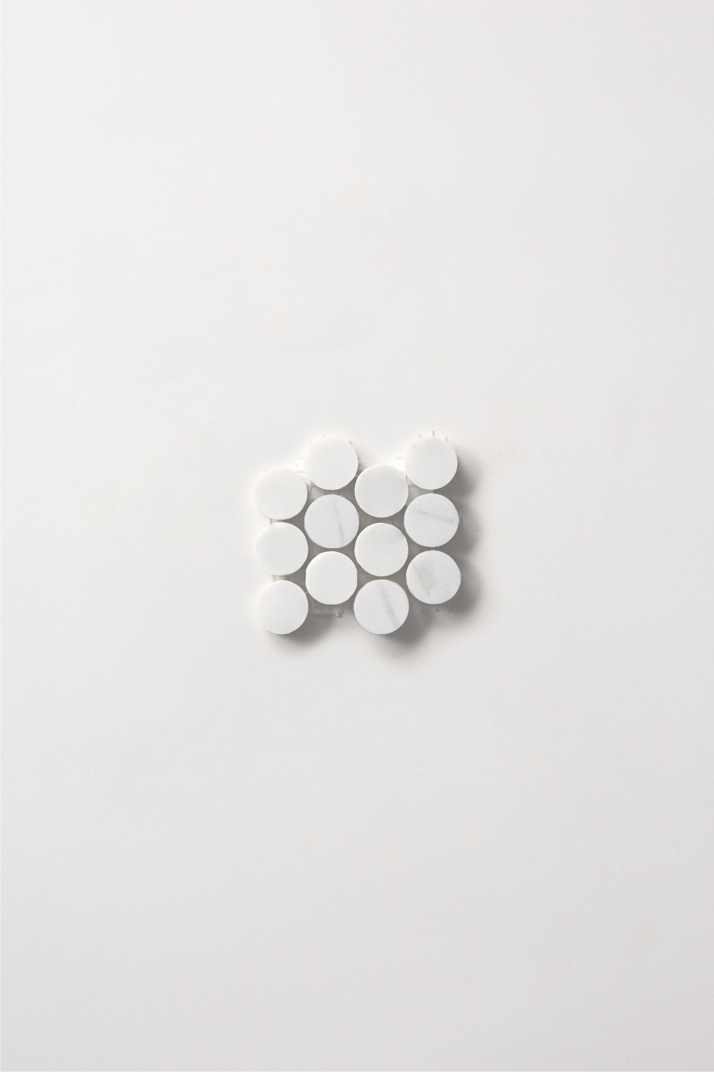 a sheet of small white penny shaped tiles on a white background.