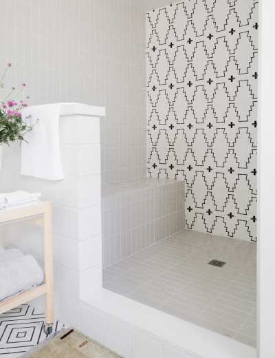 a white and black bathroom with a tiled shower.