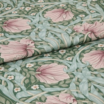 Folded woven fabric featuring a green botanical pattern of large pink flowers, pale blue-green leaves and small white blossoms, folded across the frame, showing textured weave under soft even lighting.