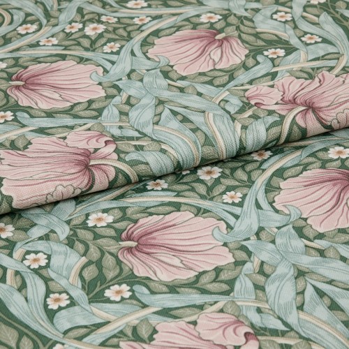 Folded woven fabric featuring a green botanical pattern of large pink flowers, pale blue-green leaves and small white blossoms, folded across the frame, showing textured weave under soft even lighting.