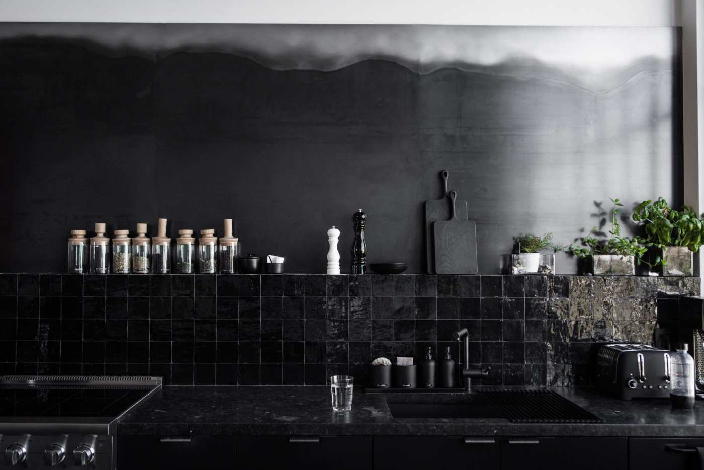 a kitchen with a black tiled wall.