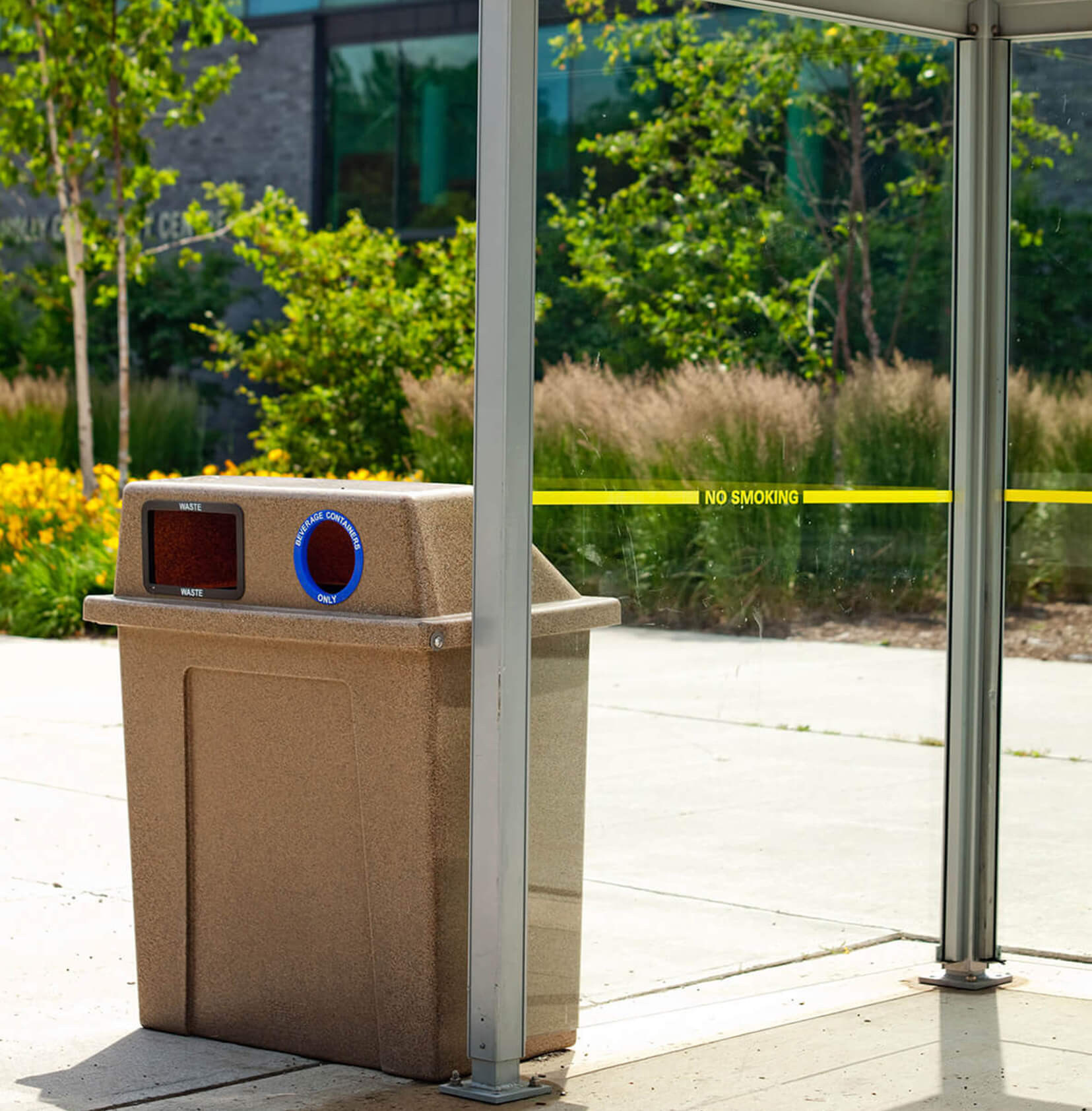 durable LDPE plastic waste and recycling container with hinged lid placed beside a transit shelter on a municipal sidewalk