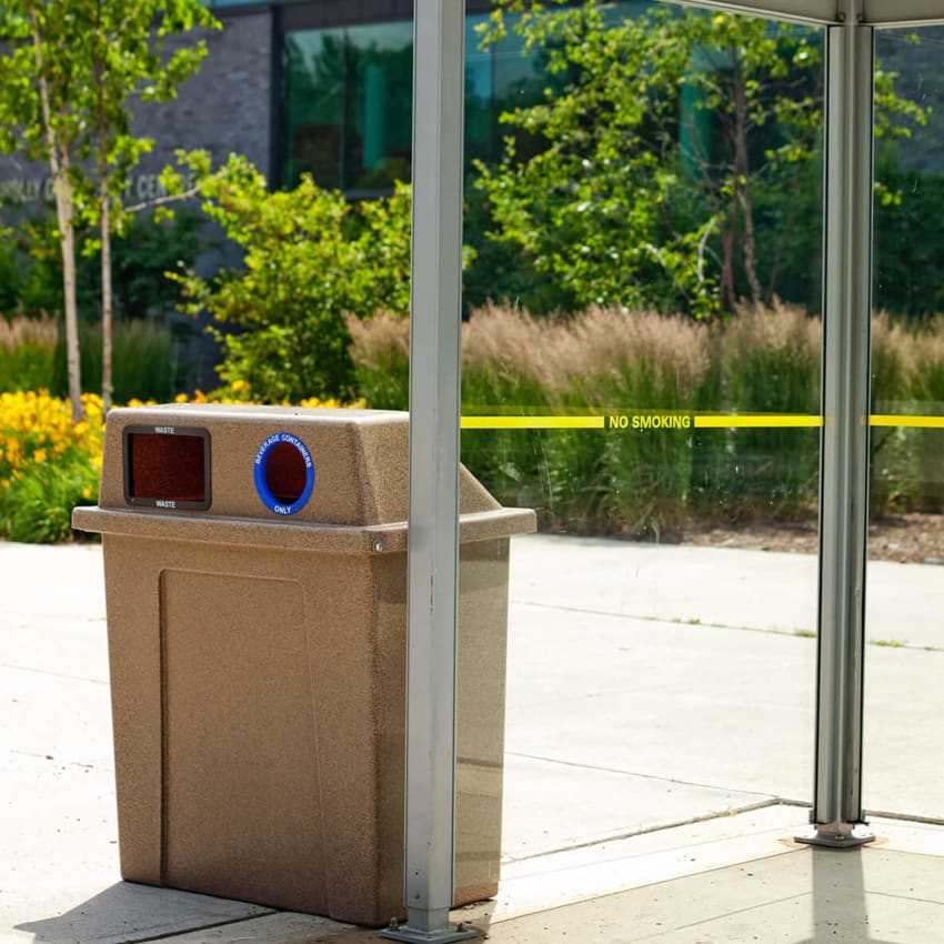 durable LDPE plastic waste and recycling container with hinged lid placed beside a transit shelter on a municipal sidewalk