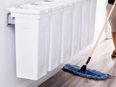 all white wall hanging trash bins with a man sweeping the floor