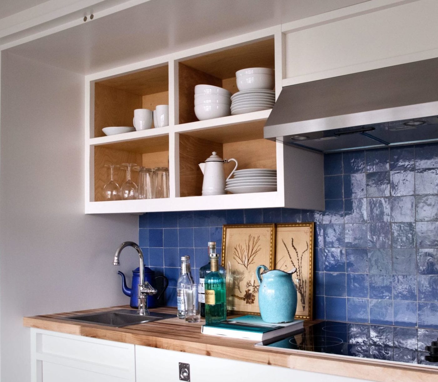 a blue tiled kitchen backsplash with a wooden counter top.