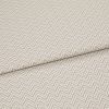Beige chevron-embossed fabric folded diagonally, showing repeated raised zigzag pattern; close-up, evenly lit textile surface emphasizing texture and subtle two-tone threads.