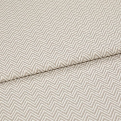 Beige chevron-embossed fabric folded diagonally, showing repeated raised zigzag pattern; close-up, evenly lit textile surface emphasizing texture and subtle two-tone threads.