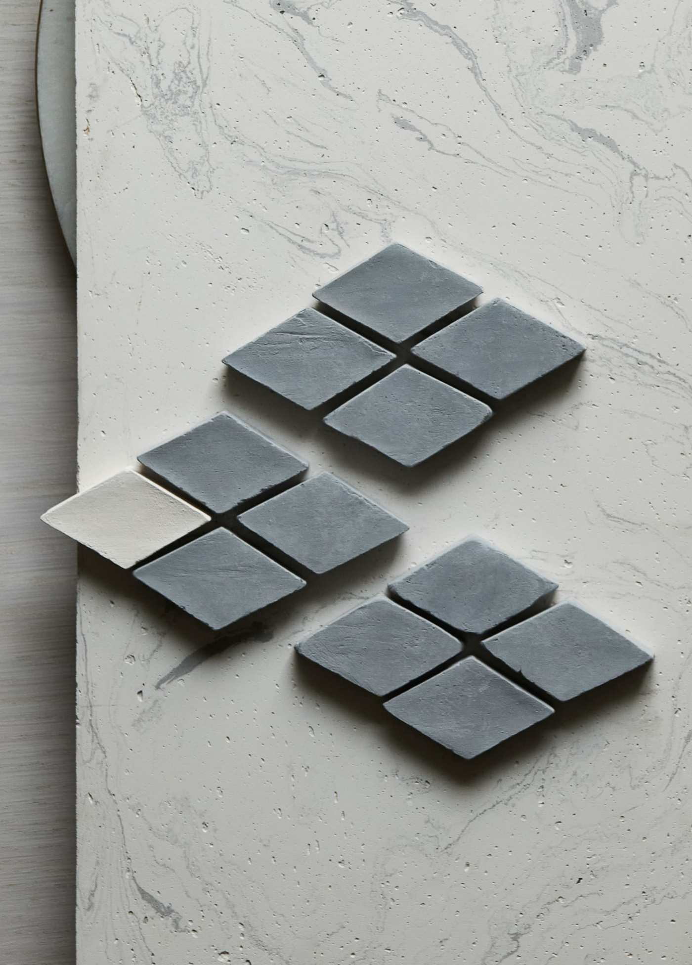 a set of small grey diamond tiles on a white surface.