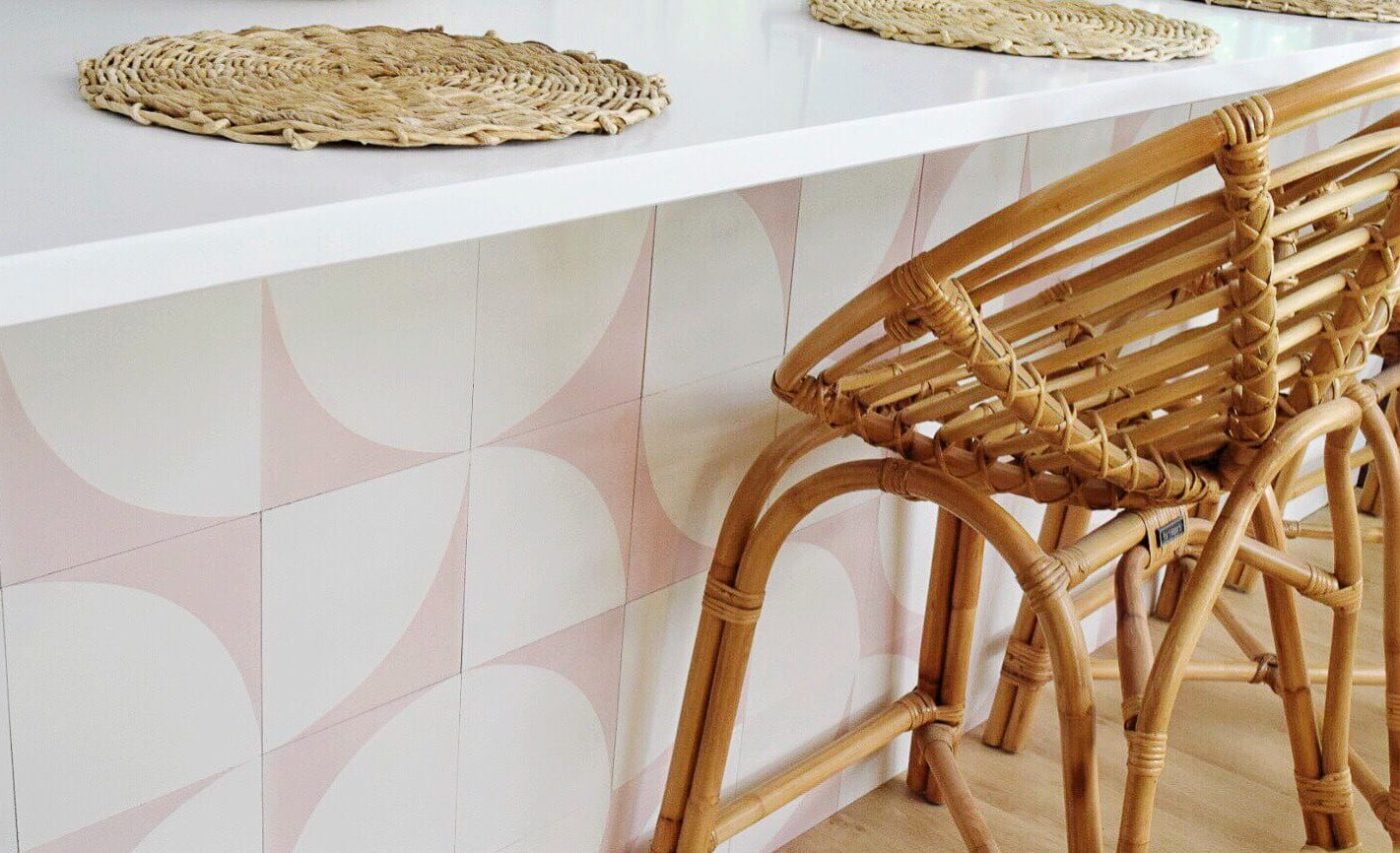 a kitchen with wicker chairs and a pink and white tiled counter.