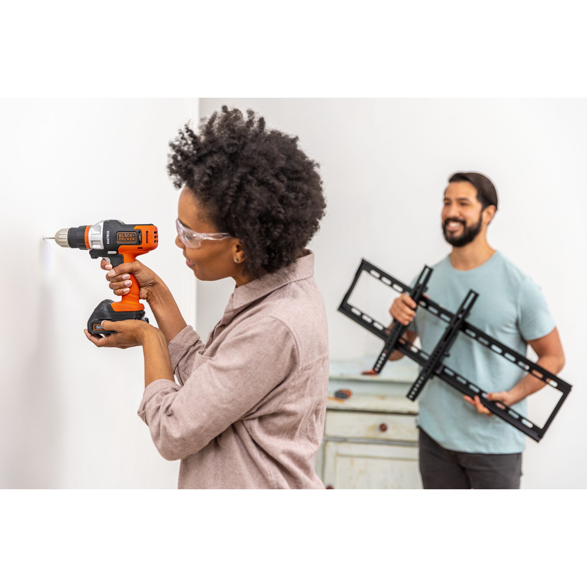 Person drills hole in to drywall to prepare to hang a TV mount using the BLACK+DECKER MATRIX drill attachment